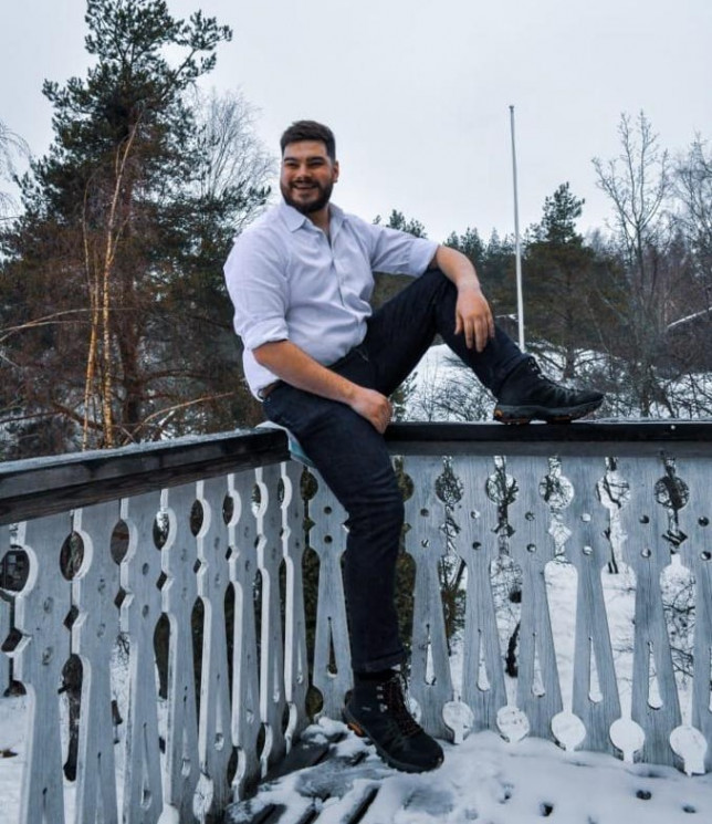 Nuori mies istuu terassin aidalla.