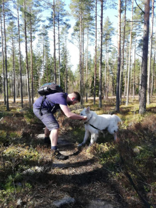 Nuori mies leikkii koiran kanssa metsässä.