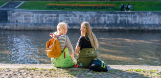 Kaksi opiskelijaa istuu Aurajoen rannassa Turussa.