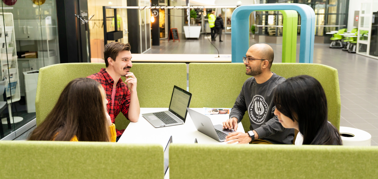 Neljä opiskelijaa keskustelee keskenään.